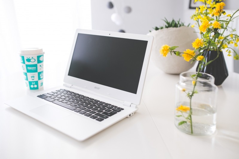 laptop-disposable-cup-and-yellow-flowers-in-vase-on-table.jpg